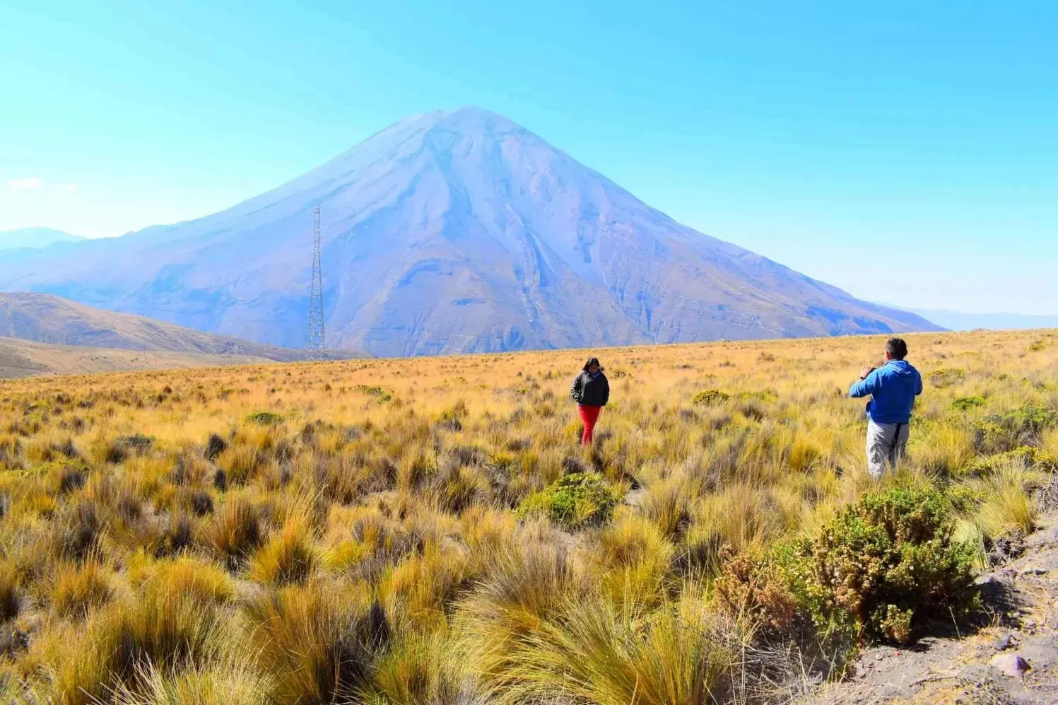 Viajeros en la puna frente a un volcán