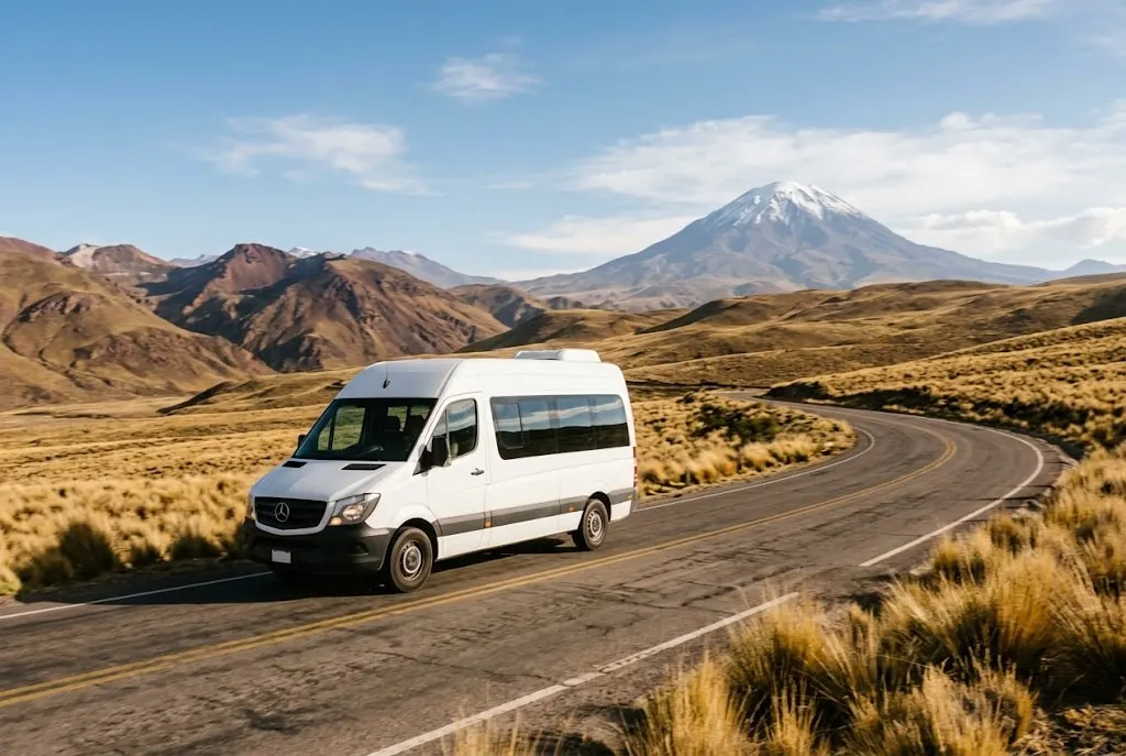 Sprinter de Suyo Tours en una carretera del altiplano frente al volcán